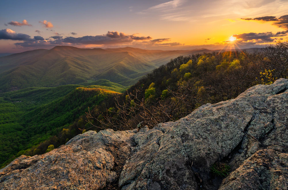 a sunset above a forest covered mountain valley