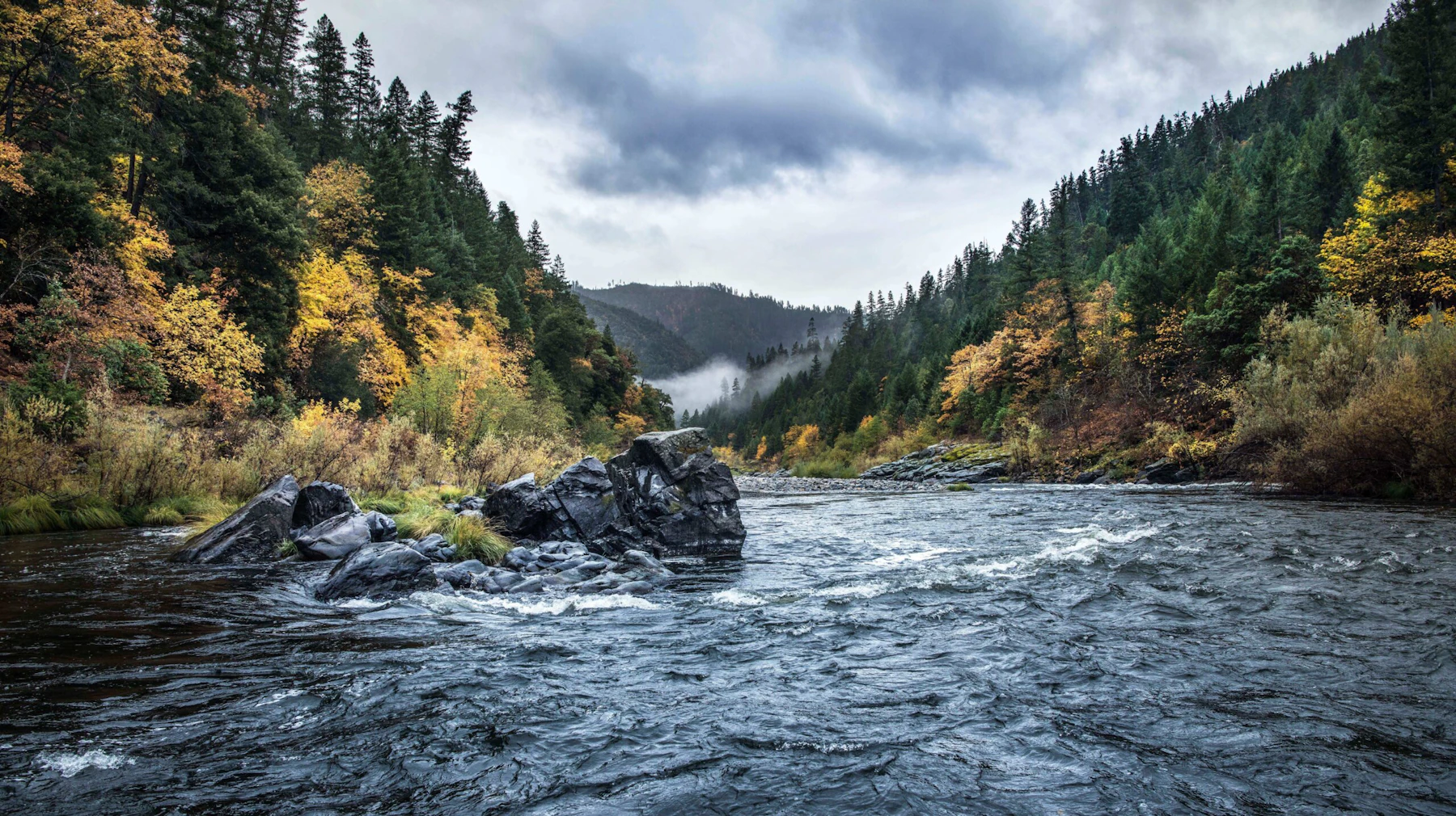 wide fast river through mountains in the fall