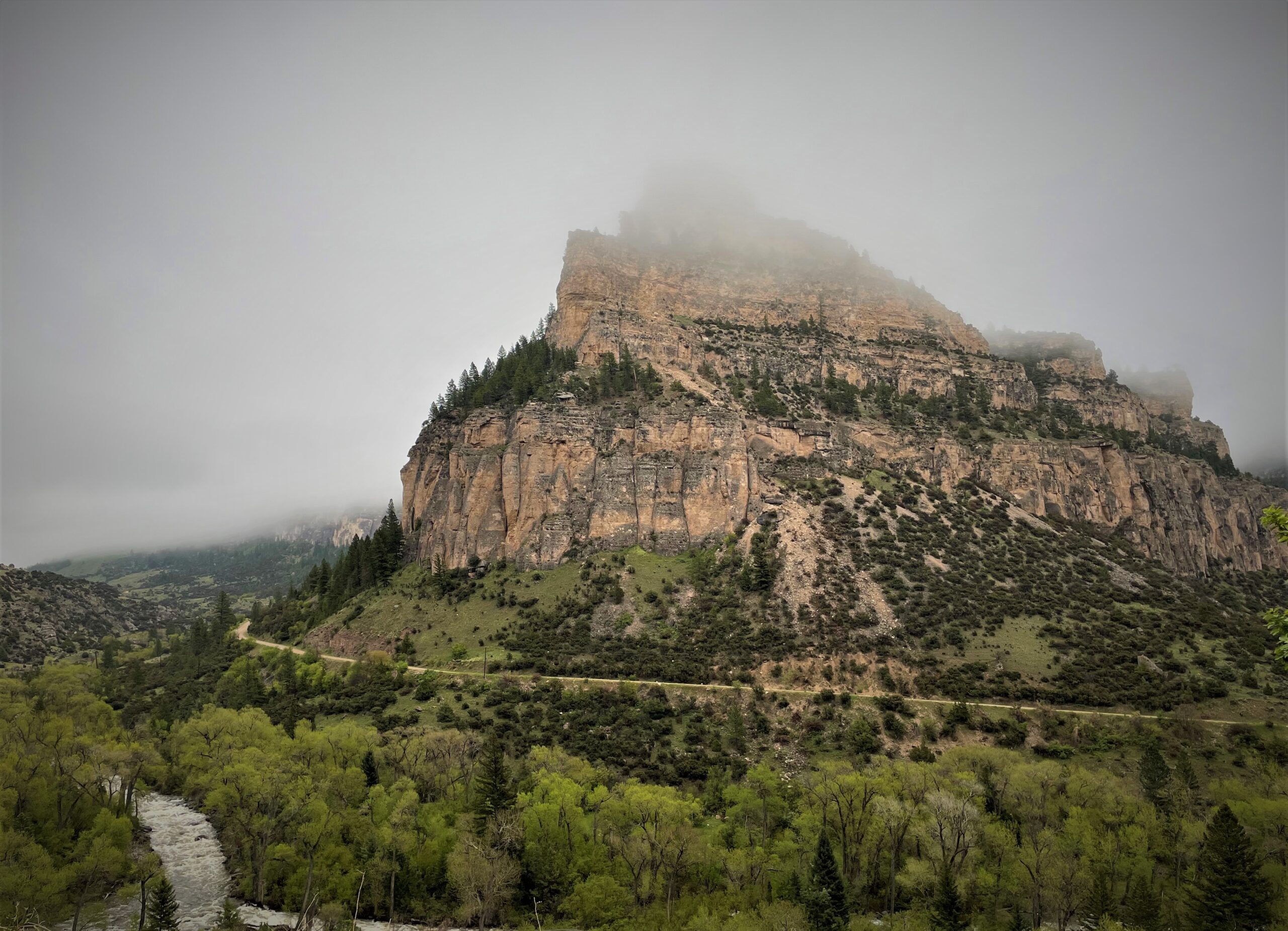 a road wraps around a misty mountain