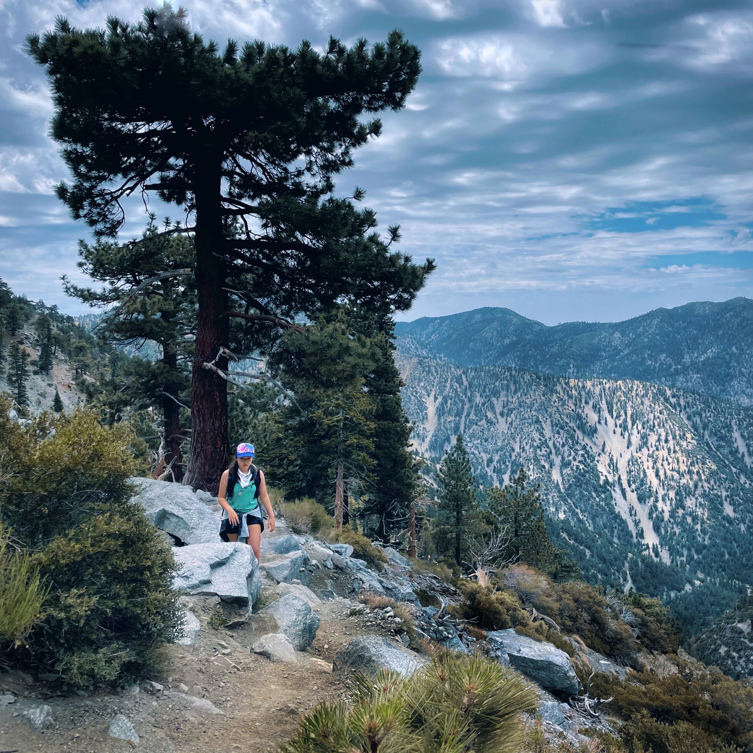 a woman hikes along a trail near the ridge line of mountains