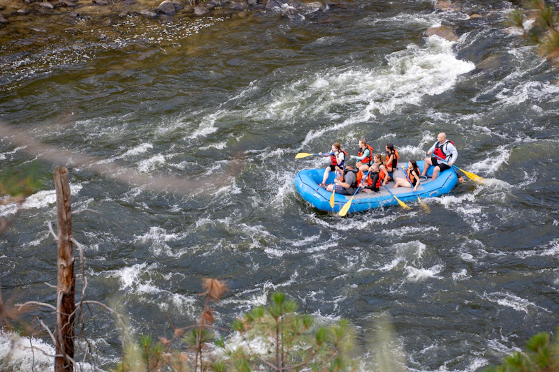 a raft full of people floats down a river with rapids