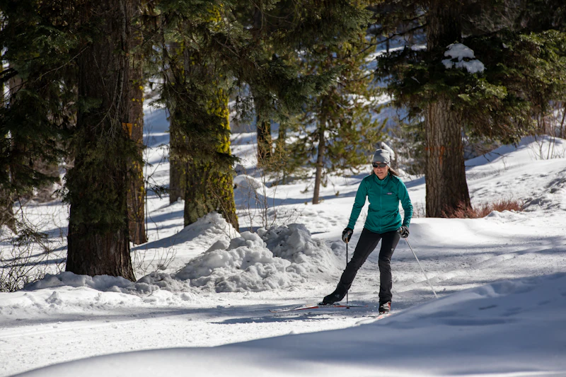 a woman cross country skis in a forest