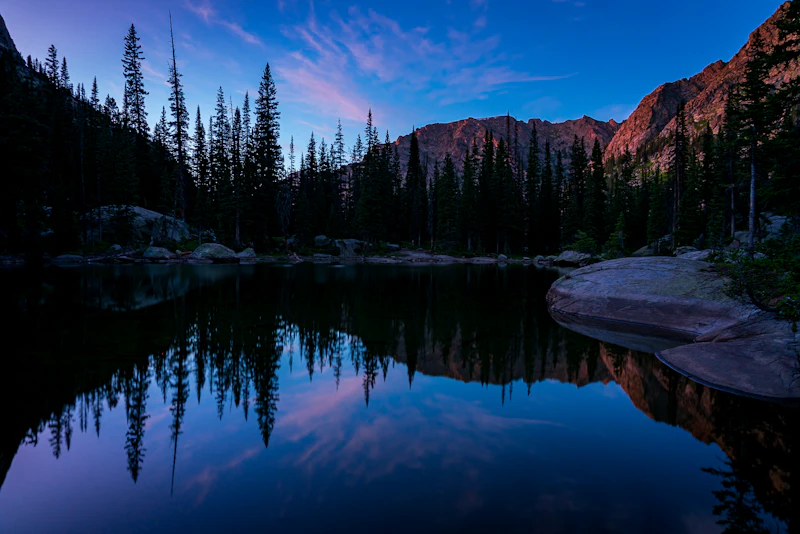 an alpine lake past sunset with pink in the sky
