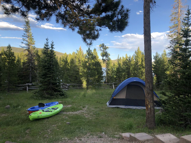a kayak and tent at a campsite in the forest at a lake