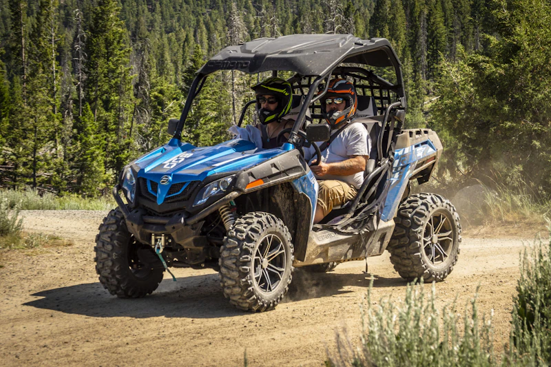 a family rides in a side by side off road vehicle on a dirt road