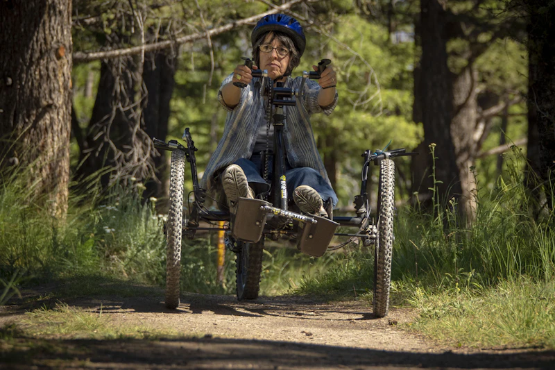a woman uses a hand bike on a forest trail