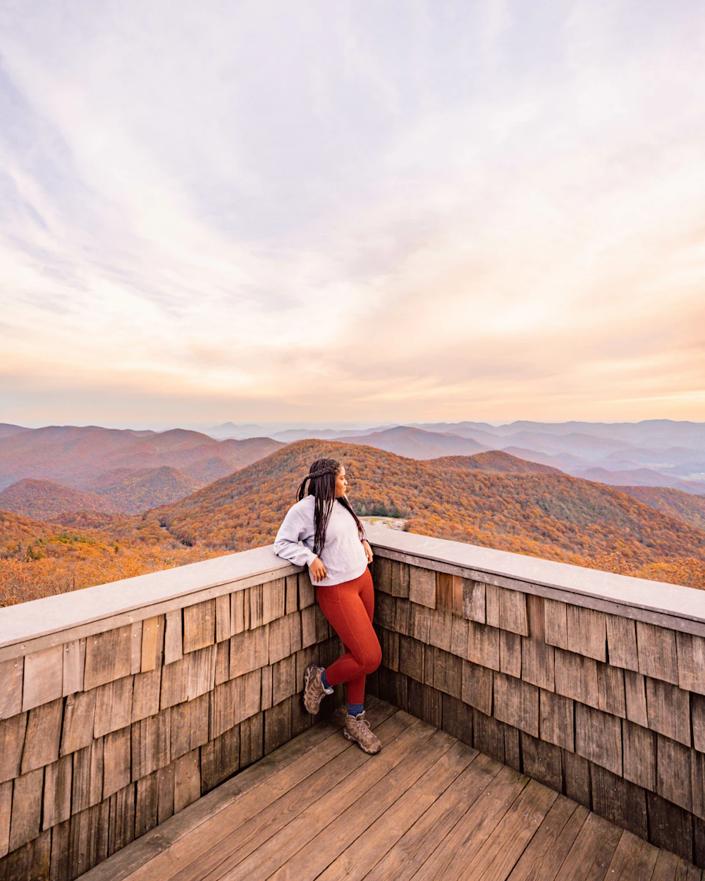 woman stands at an overlook above the mountains in fall