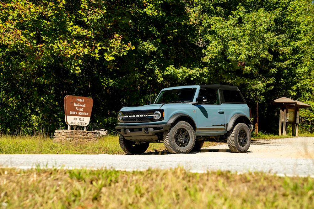 parked vehicle in front of a forest sign