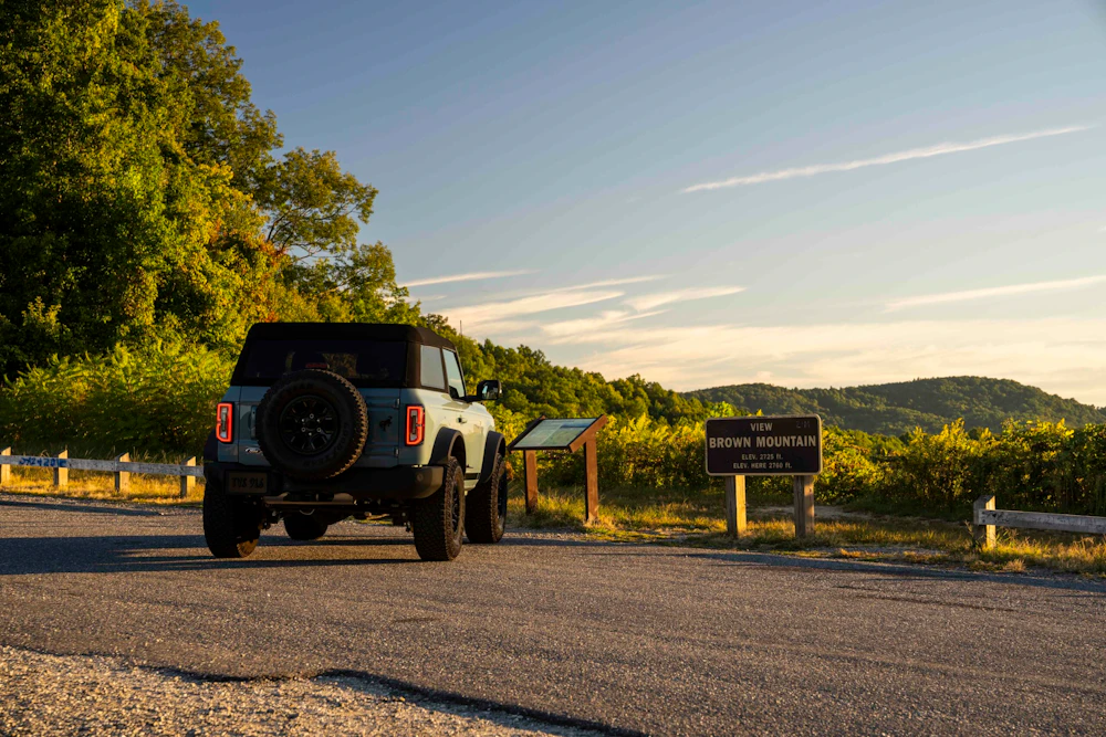 parked vehicle near signs in the forest