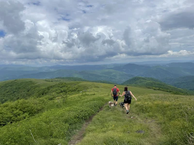 hikers descend a dirt trail atop a mountain