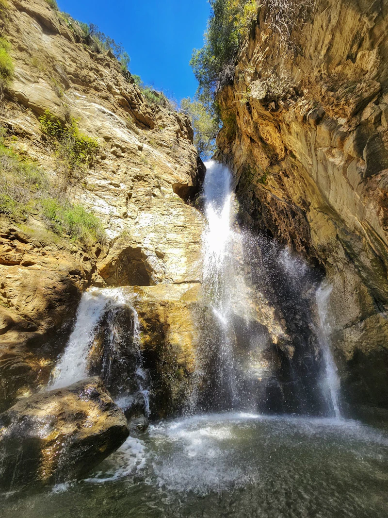 a small waterfall cascades into a pool in a rocky canyon