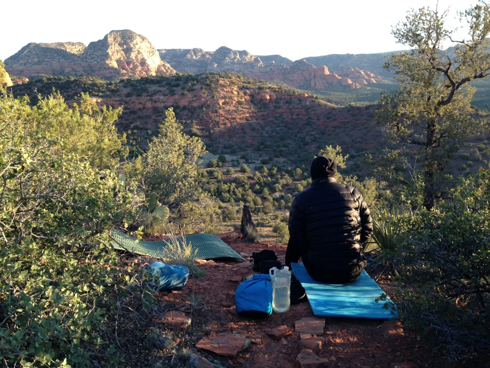 a hiker sits on a mat on the ground in a desert