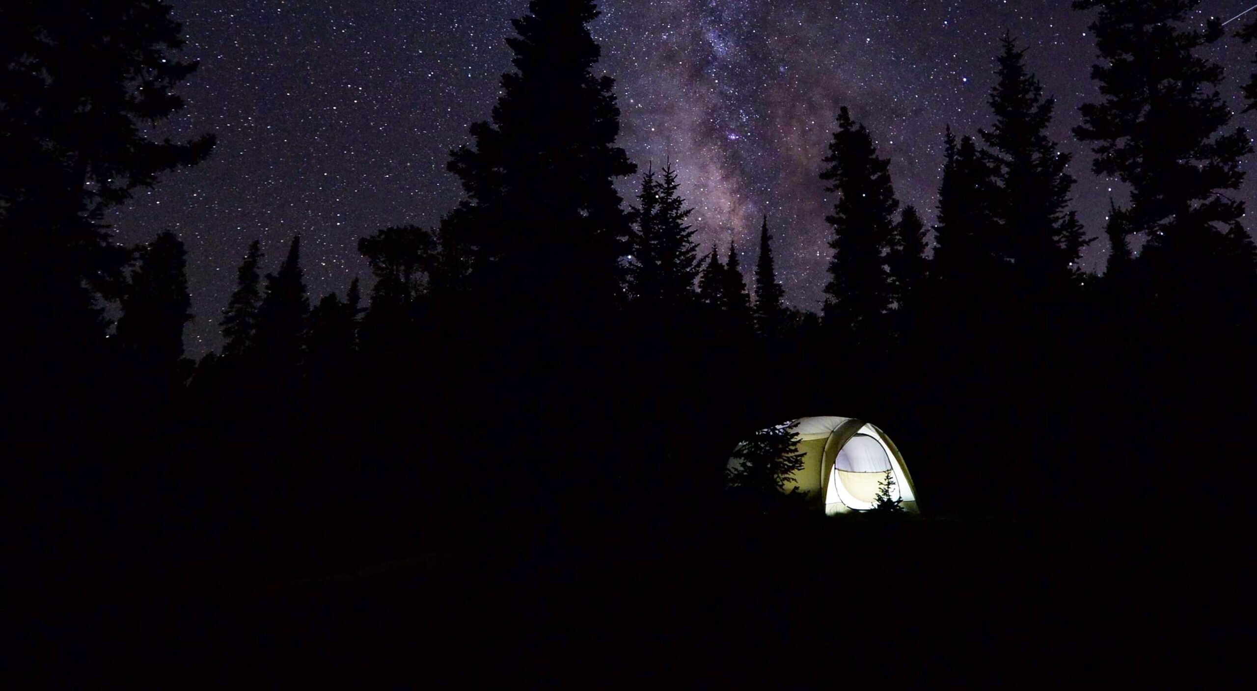 Glowing tent under a stary night sky.