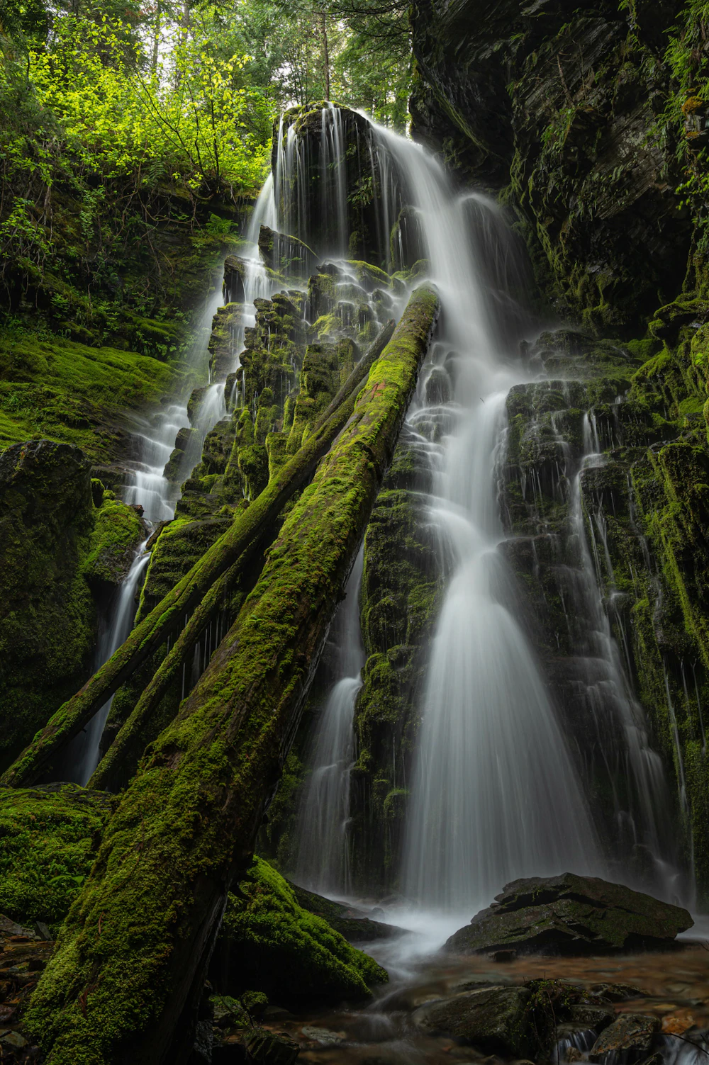 large waterfall down rocks in a mossy green forest