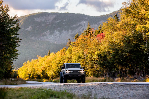 Ford Bronco driving on a scenic byway through the White Mountain National Forest.