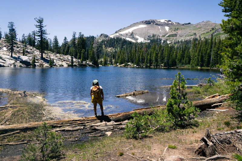 Woman stands on the shore of an alpine lake.