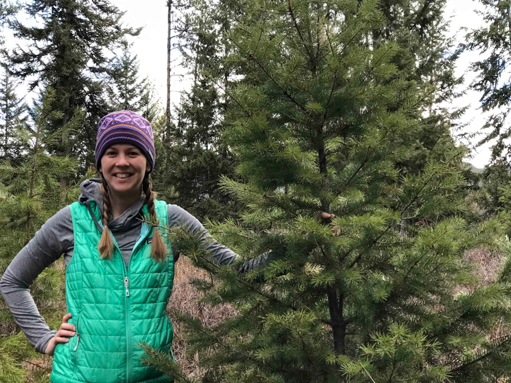 woman standing next to a pine tree