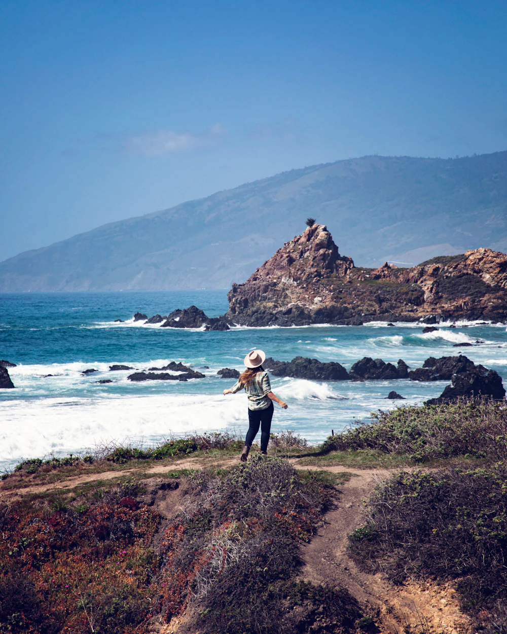 a woman at the end of the trail near the beach by the ocean