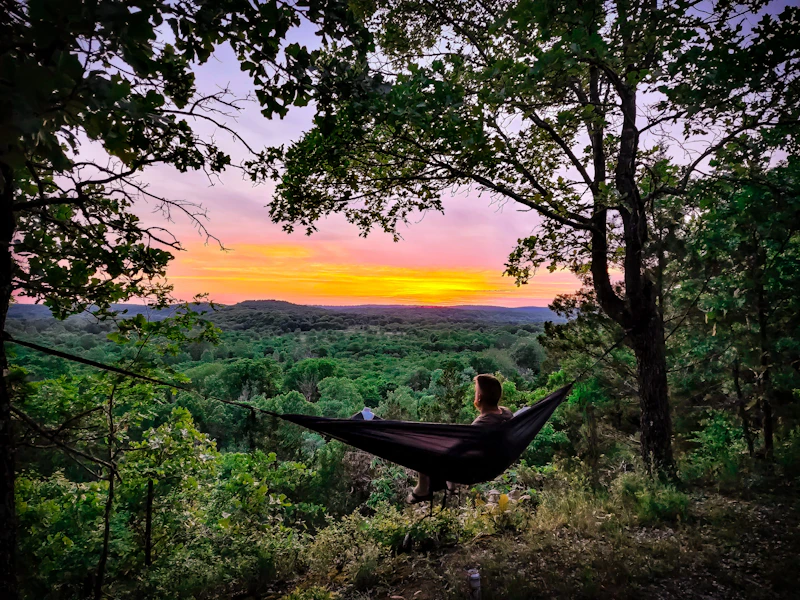 Man watches the sunset from a hammock.