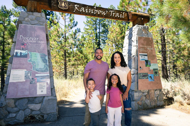 A family poses at the entrance to the Rainbow Trail at Taylor Creek Visitor Center, flanked by new interpretive signage highlighting Tahoe's unique ecology and wetland habitats.