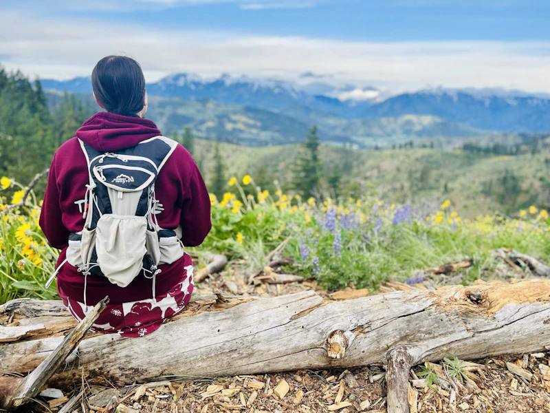 Woman rising on a log surrounded by wildflowers.