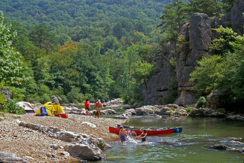 Campers canoe and swim in the river.
