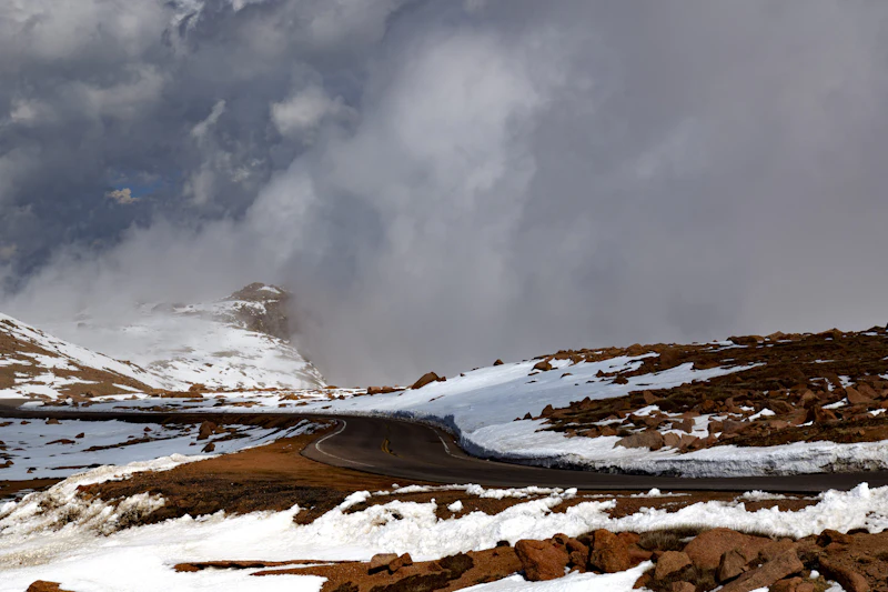 Alpine road winding through snow and mist.