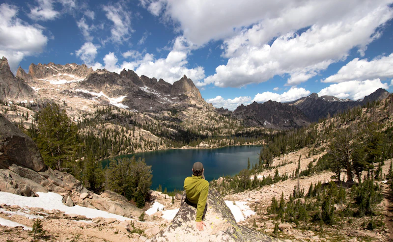 Hiker sitting on a rock overlooking a lake.