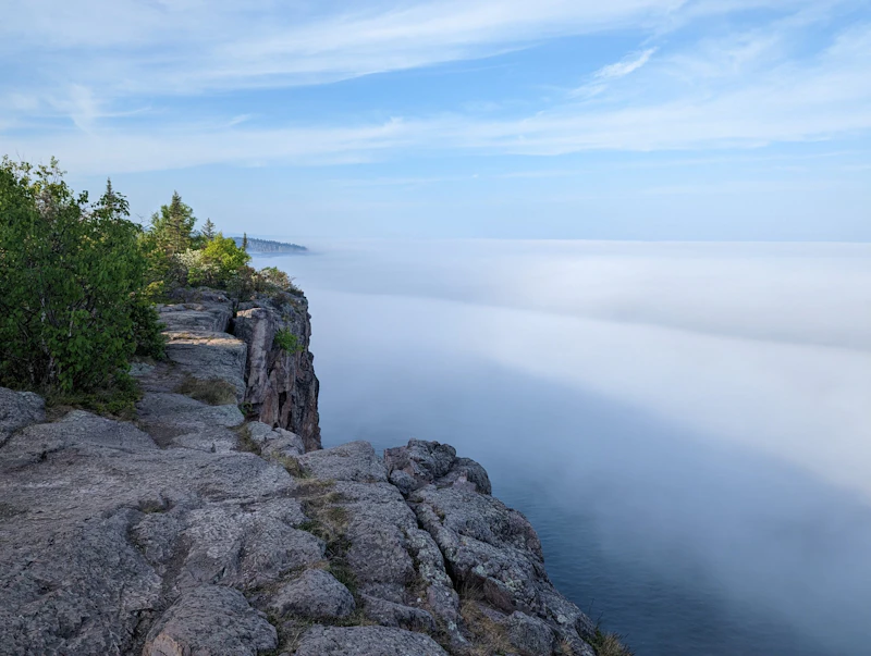 Cloudy view of a lake from a cliff side.