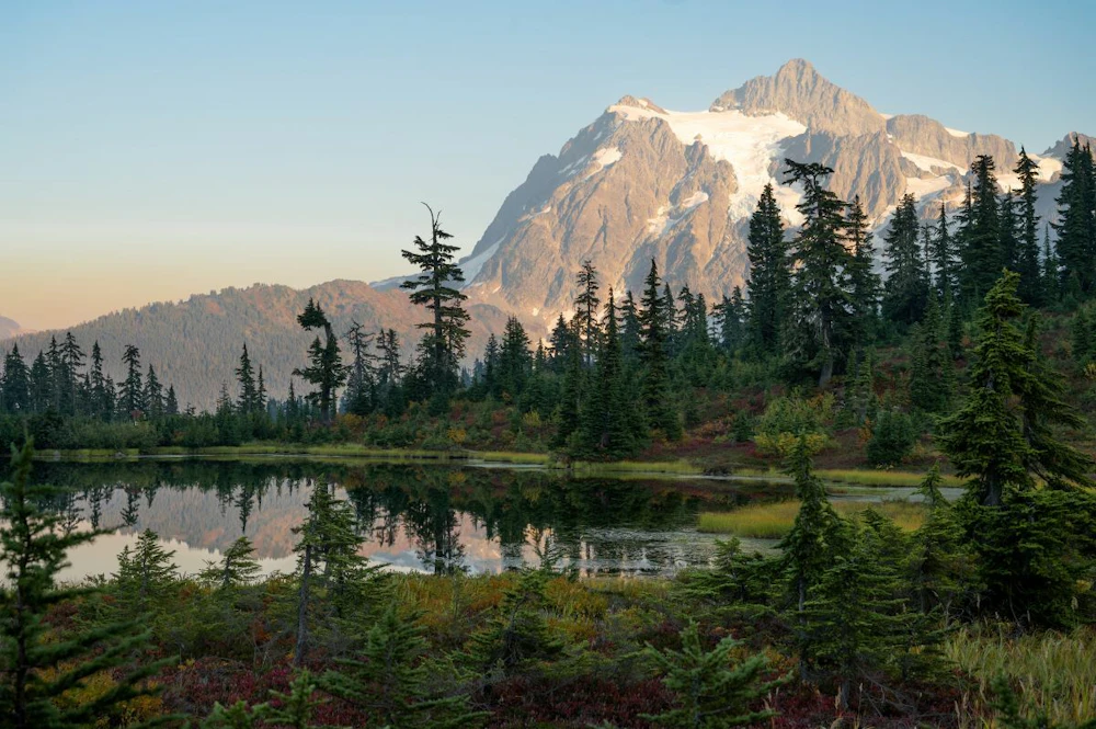 a large mountain behind a small pond
