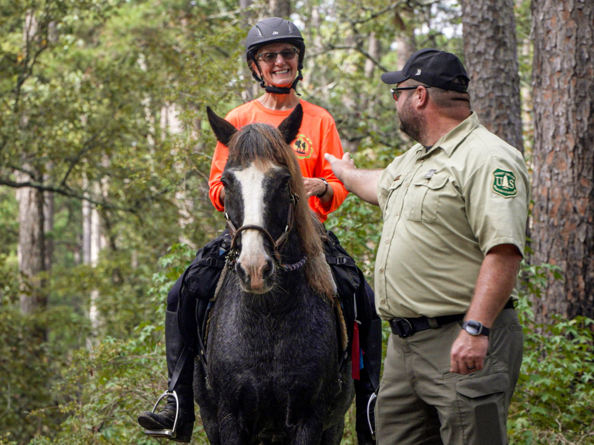 Woman on horseback being guided by a Forest Service Ranger.