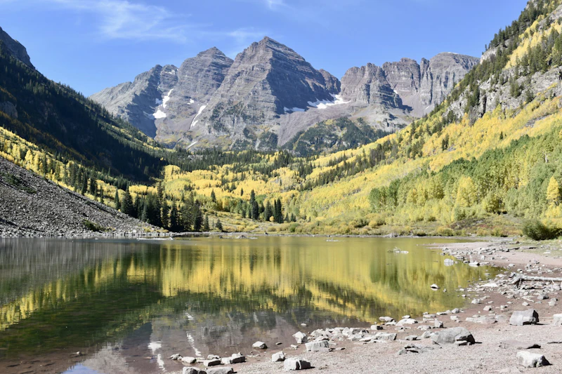 sharp mountain peaks in front of an alpine lake and yellow aspen trees