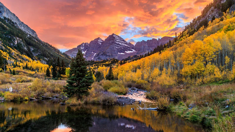 alpine lake in front of dramatic mountain peaks during fall and at sunset
