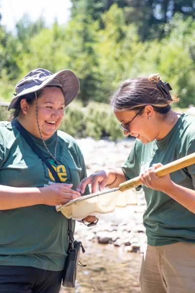 Two girls examine an aquatic specimen in a net.