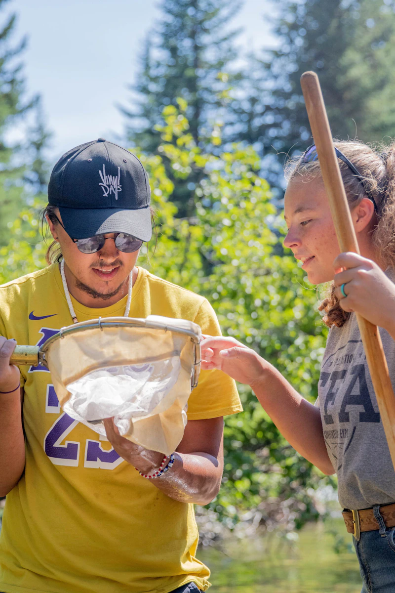 two young adults view items in a net in the forest
