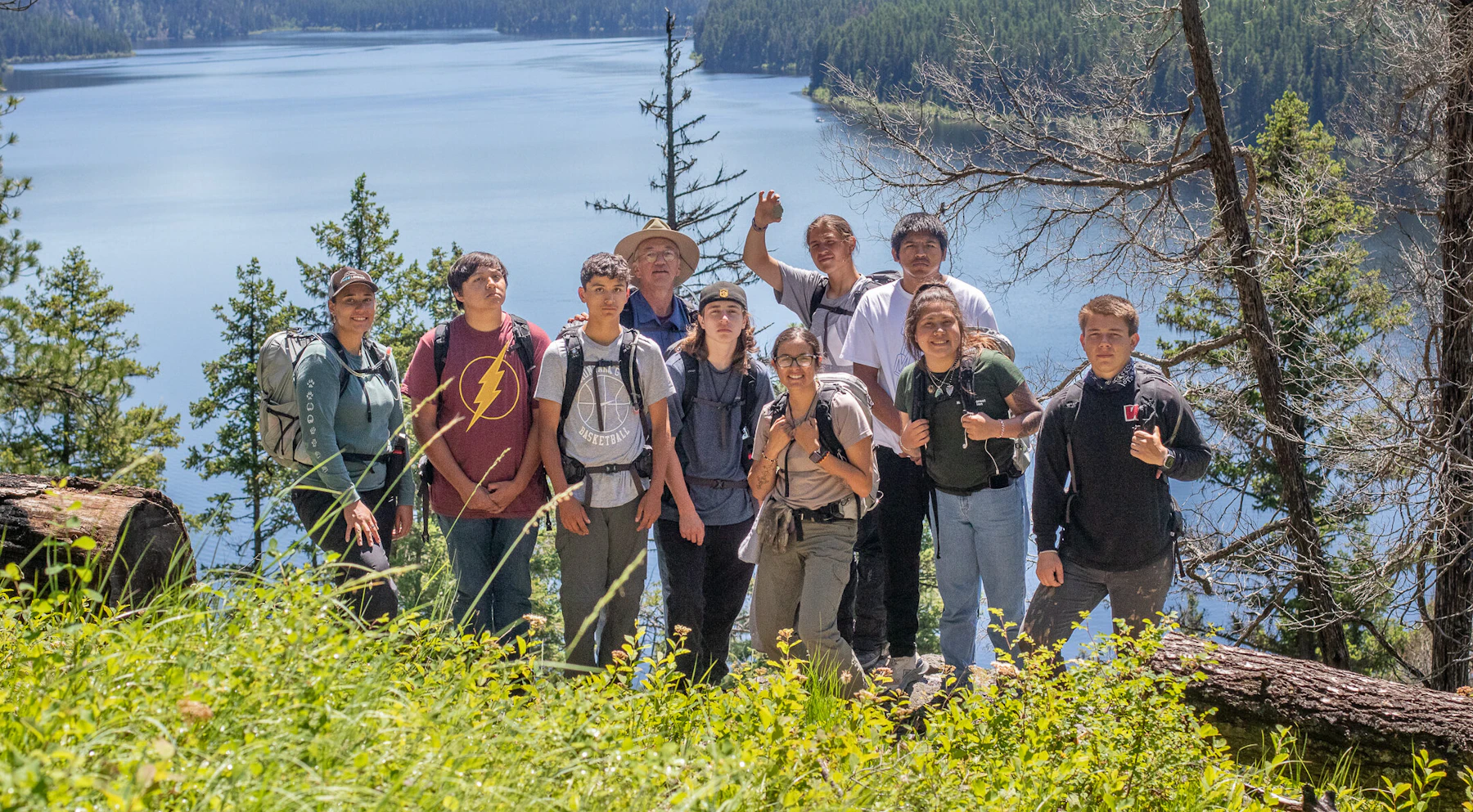 2022 Mission Mountain Youth Crew pose together in front of a lake.