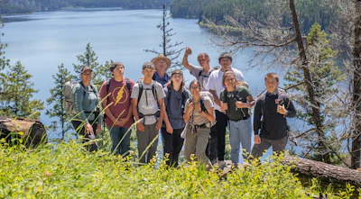 2022 Mission Mountain Youth Crew pose together in front of a lake.