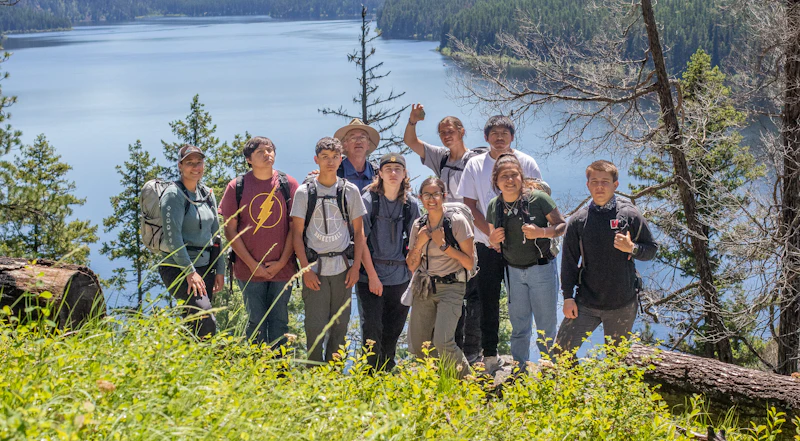2022 Mission Mountain Youth Crew pose together in front of a lake.