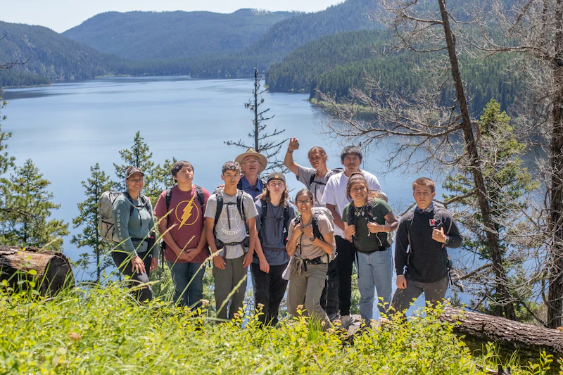 group photo posing of young adults above a forest lake