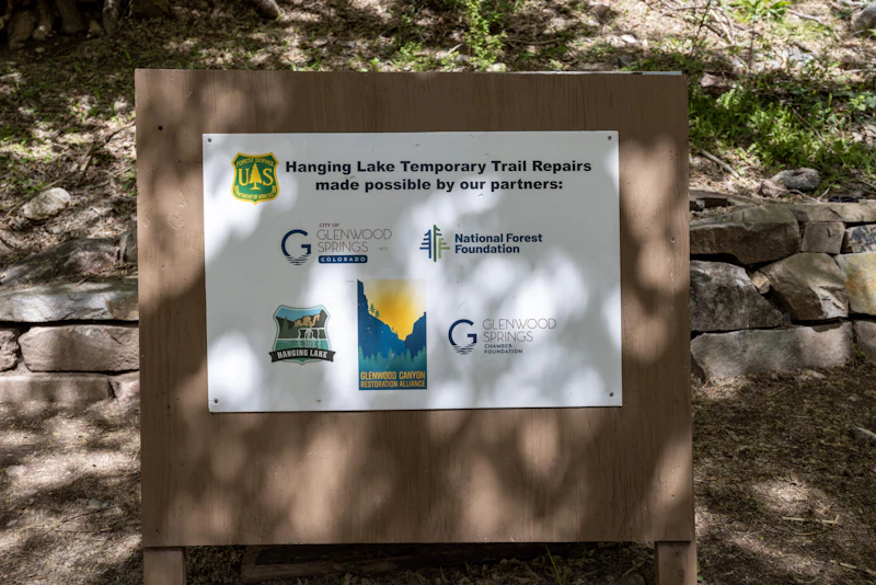 U.S. Forest Service sign that reads: "Hanging Lake temporary trail repairs made possible by the City of Glenwood Springs, National Forest Foundation, Hanging Lake, Glenwood Canyon Restoration Alliance, and Glenwood Springs Chamber Foundation."