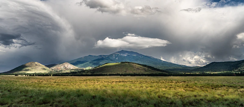 Sweeping view of flat grasslands leading into soaring mountain peeks.