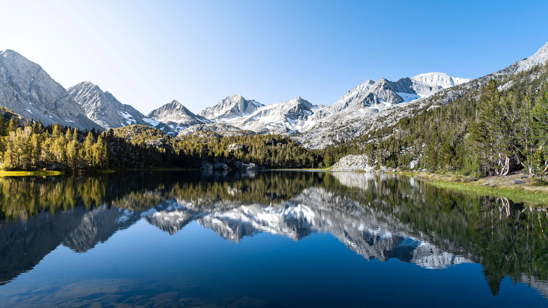 an alpine lake reflects mountains