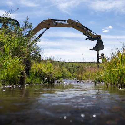 large machinery works on water restoration in a meadow